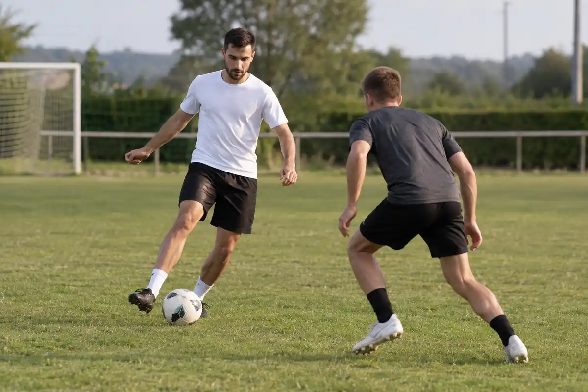 Deux joueurs se disputent le ballon en entraînement, illustrant comment un profil consultable pourrait faciliter leur repérage à distance.
