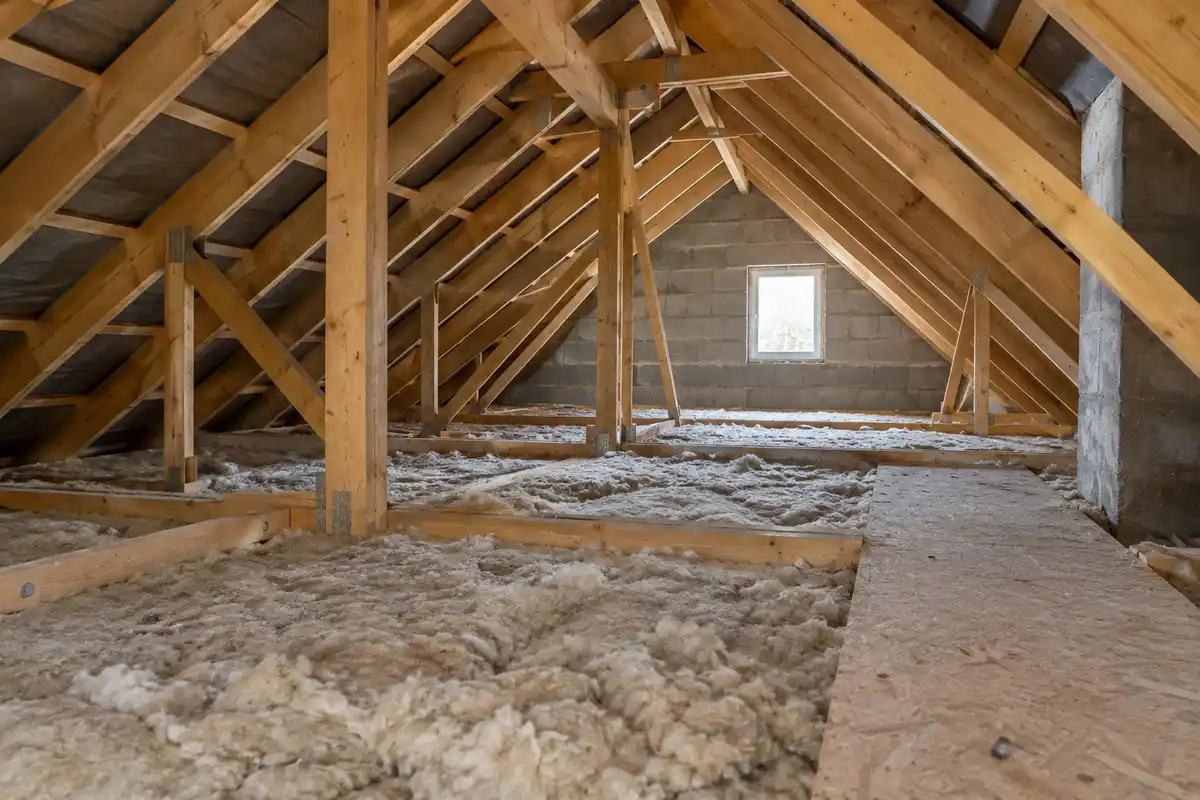 Dans des combles perdus, l’isolant recouvre le plancher sous la charpente, une configuration à distinguer des murs et de la façade.